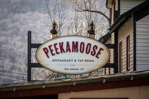 Sign for Peekamoose Restaurant & Tap Room in Big Indian, NY, with a scenic mountain backdrop.