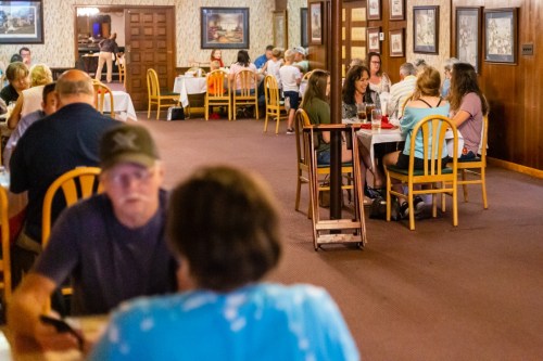A busy restaurant interior with families and groups dining at tables, creating a lively atmosphere.