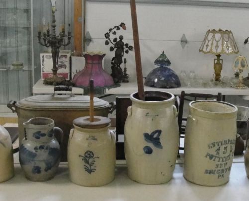 A collection of vintage ceramic jars and containers with decorative designs, displayed in a shop setting.