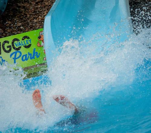 A person splashes into a pool from a water slide, with a sign for "Water Valley Park" in the background.