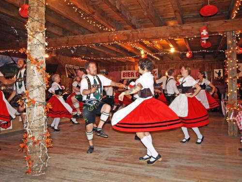 A lively dance scene with people in traditional attire, twirling in a festive, decorated hall.