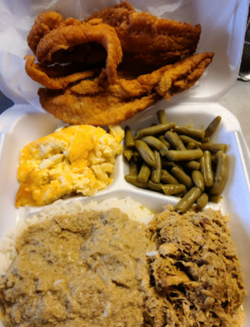 A takeout container with fried fish, rice with gravy, green beans, and a cheesy casserole.