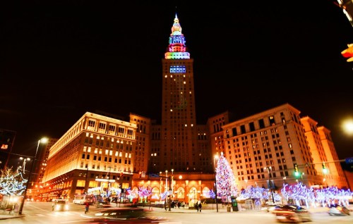 A brightly lit cityscape at night featuring a tall building with colorful lights and festive decorations.