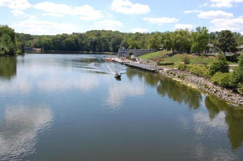 A serene river scene with a boat gliding across the water, surrounded by lush greenery and a clear blue sky.