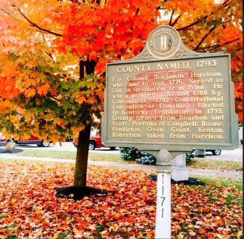 A historical marker about Colonel Benjamin Harrison, surrounded by vibrant autumn leaves.