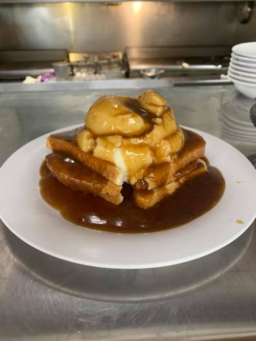 A plate of stacked toast topped with a mound of creamy dessert and drizzled with caramel sauce.