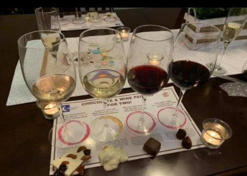 A table set with five wine glasses, chocolates, and a tasting menu for a chocolate and wine pairing event.