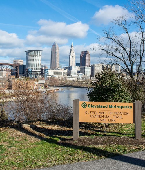 View of downtown Cleveland skyline with the Cleveland Foundation Centennial Trail sign in the foreground.