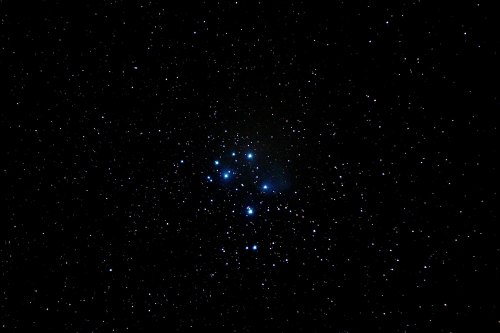 A cluster of bright blue stars surrounded by a dark, starry sky.