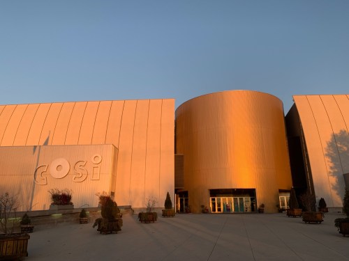 Exterior of GOSI building at sunset, featuring a large cylindrical structure and warm golden lighting.
