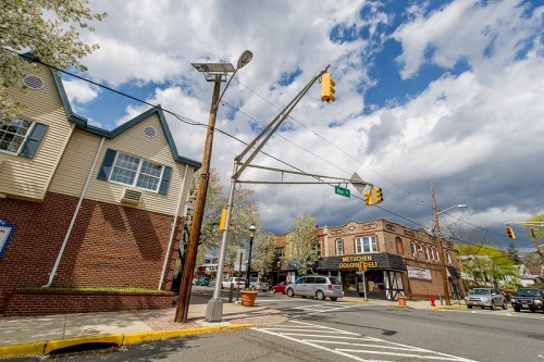 A street view showing a traffic light, buildings, and a cloudy sky in a small town setting.