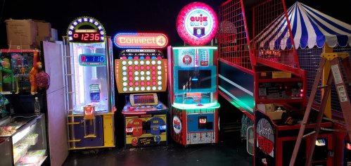 A colorful arcade featuring various games, including Connect 4 and a basketball shooting game, in a fun setting.