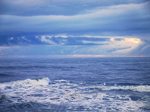 A serene ocean scene with gentle waves under a cloudy sky, creating a calm and tranquil atmosphere.