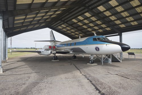 A vintage aircraft displayed under a hangar, featuring a blue and white color scheme with the words "United States of America."