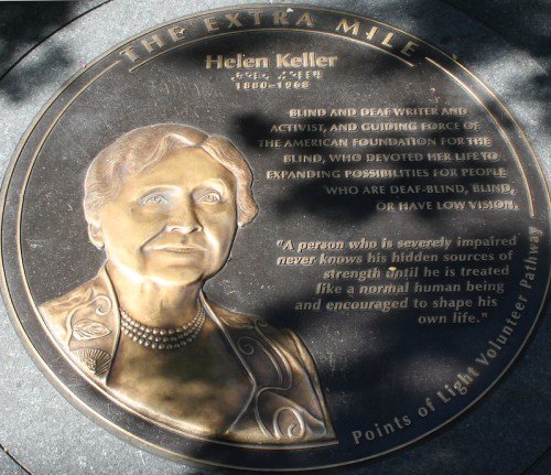 Bronze plaque honoring Helen Keller, featuring her portrait and a quote about strength and normalcy for the disabled.