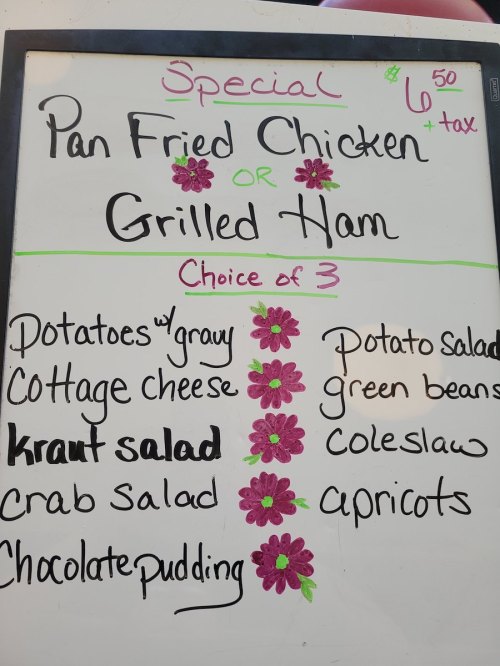 Menu board listing a special: Pan Fried Chicken or Grilled Ham with sides like potatoes, kraut salad, and chocolate pudding.
