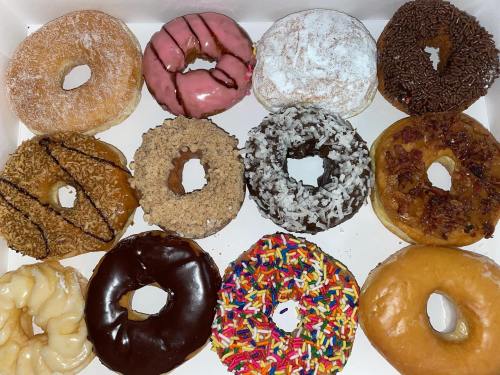 A box of assorted donuts, featuring various flavors and toppings, including sprinkles, chocolate, and coconut.