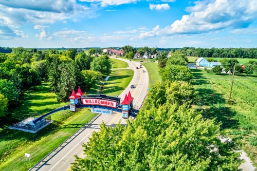 Aerial view of a welcoming sign for Frankenmuth, surrounded by lush greenery and a clear blue sky.