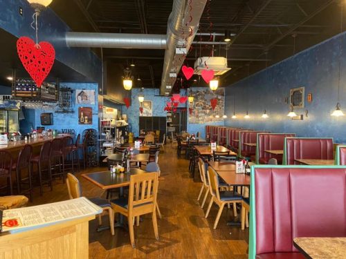 Cozy restaurant interior with red booths, wooden tables, and heart decorations hanging from the ceiling.