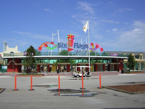 Entrance to Six Flags amusement park, featuring colorful signage and a clear blue sky.