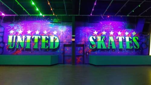 Colorful wall with the words "UNITED SKATES" and festive decorations, set in a roller skating rink.