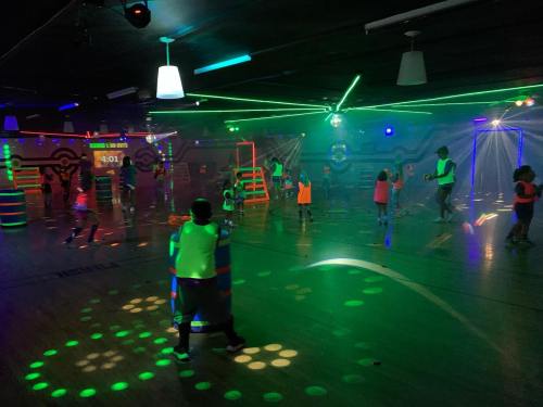 A vibrant indoor roller skating rink with neon lights, colorful decorations, and people skating in bright outfits.