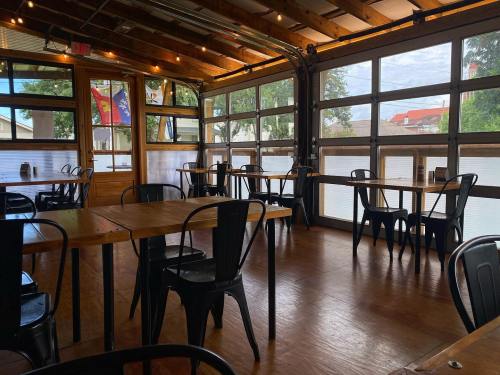 Interior of a rustic restaurant with wooden tables, metal chairs, and large windows letting in natural light.