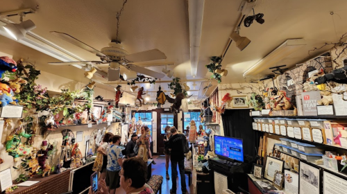A vibrant shop filled with colorful dolls and decorations, with visitors exploring the unique displays.