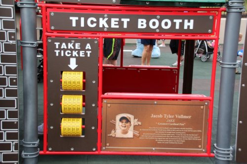 A colorful ticket booth with a ticket dispenser and a plaque featuring Jacob Tyler Vollmer's name and details.