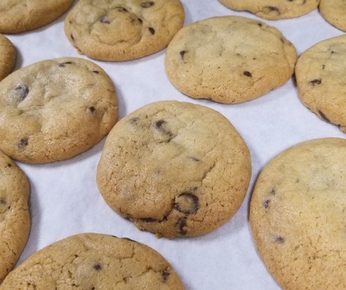 Freshly baked chocolate chip cookies arranged on parchment paper.