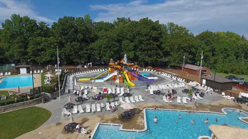 Aerial view of a vibrant water park with slides, pools, and lounge chairs surrounded by trees.