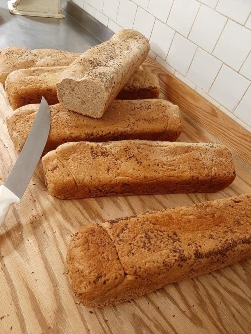 Freshly baked loaves of bread on a wooden surface, with a knife resting nearby.