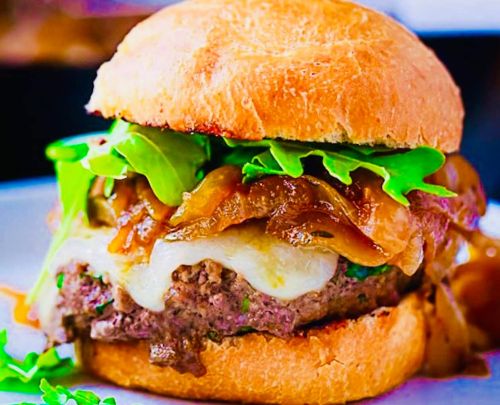 A juicy burger with melted cheese, caramelized onions, and fresh greens, served in a toasted bun.