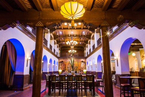 Elegant interior of a spacious restaurant with wooden beams, arches, and a central bar area illuminated by warm lighting.