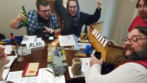 A group of friends joyfully playing a tabletop game, with drinks and game materials on the table. Excitement fills the room.