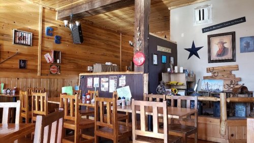 Cozy restaurant interior with wooden tables, chairs, and rustic decor, featuring a star and framed artwork on the walls.