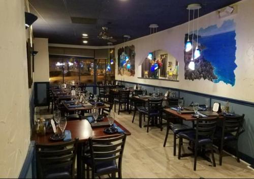 Interior of a restaurant with tables set for dining, blue walls, and ocean-themed artwork. Soft lighting creates a cozy atmosphere.