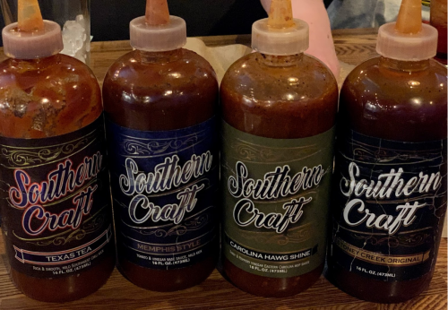 Four bottles of Southern Craft barbecue sauces labeled Texas Tea, Memphis Style, Carolina Hawg Shine, and Honey Creek Original.