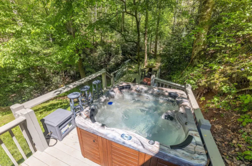 A hot tub on a wooden deck surrounded by lush green trees and a serene natural setting.
