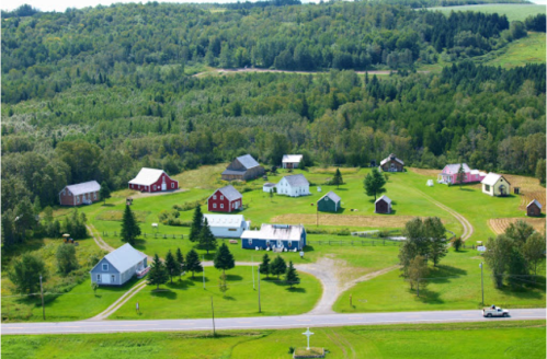 Aerial view of a rural village with colorful houses surrounded by lush greenery and trees.