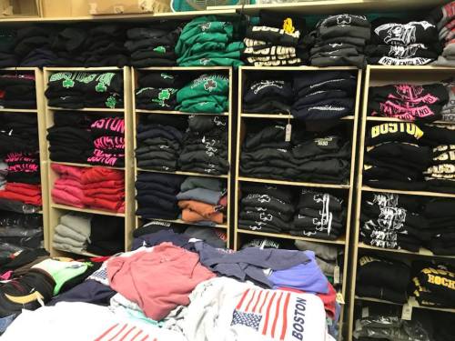 A display of neatly stacked t-shirts in various colors and designs on shelves and tables.