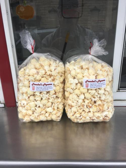 Two large bags of popcorn sit on a counter, labeled "Janelle's Popcorn" with a red and white logo.