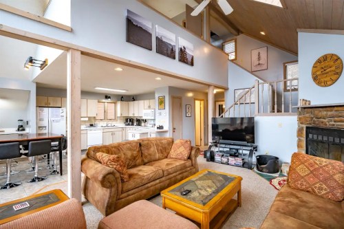 Cozy living room with a sofa, coffee table, and stairs leading to an upper level, featuring a kitchen in the background.
