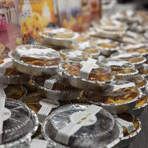 A display of various baked pies in aluminum foil containers, stacked neatly on a table.