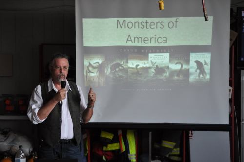 A speaker presents "Monsters of America" with book covers displayed on a screen in a workshop setting.