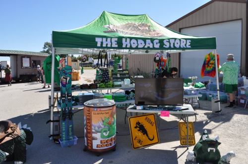 A colorful tent labeled "The Hodag Store" displays various merchandise, including shirts and signs, at an outdoor event.