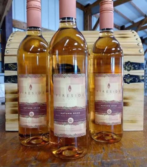 Three bottles of Fireside Autumn Spice wine are displayed in front of a wooden crate.