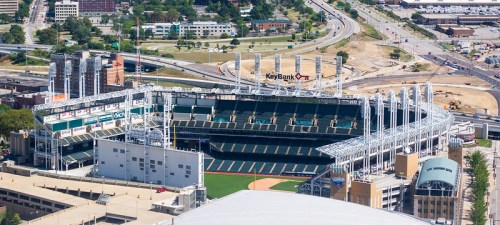 Aerial view of a baseball stadium with seating, field, and surrounding urban landscape.