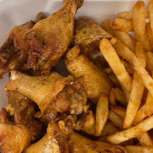 A close-up of crispy fried chicken wings next to a serving of golden French fries.
