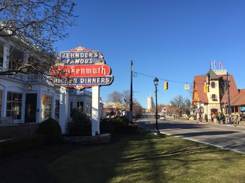 A street view of Frankenmuth, Michigan, featuring a sign for Zehnder's and charming buildings under a clear blue sky.